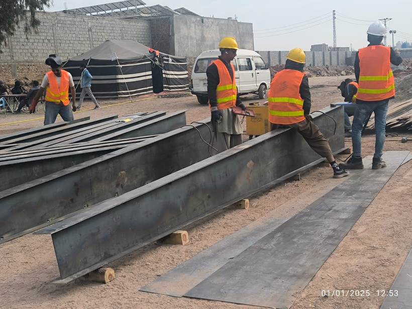 Workers welding large structural steel beams on an industrial site, Al Azeem Engineering Islamabad
